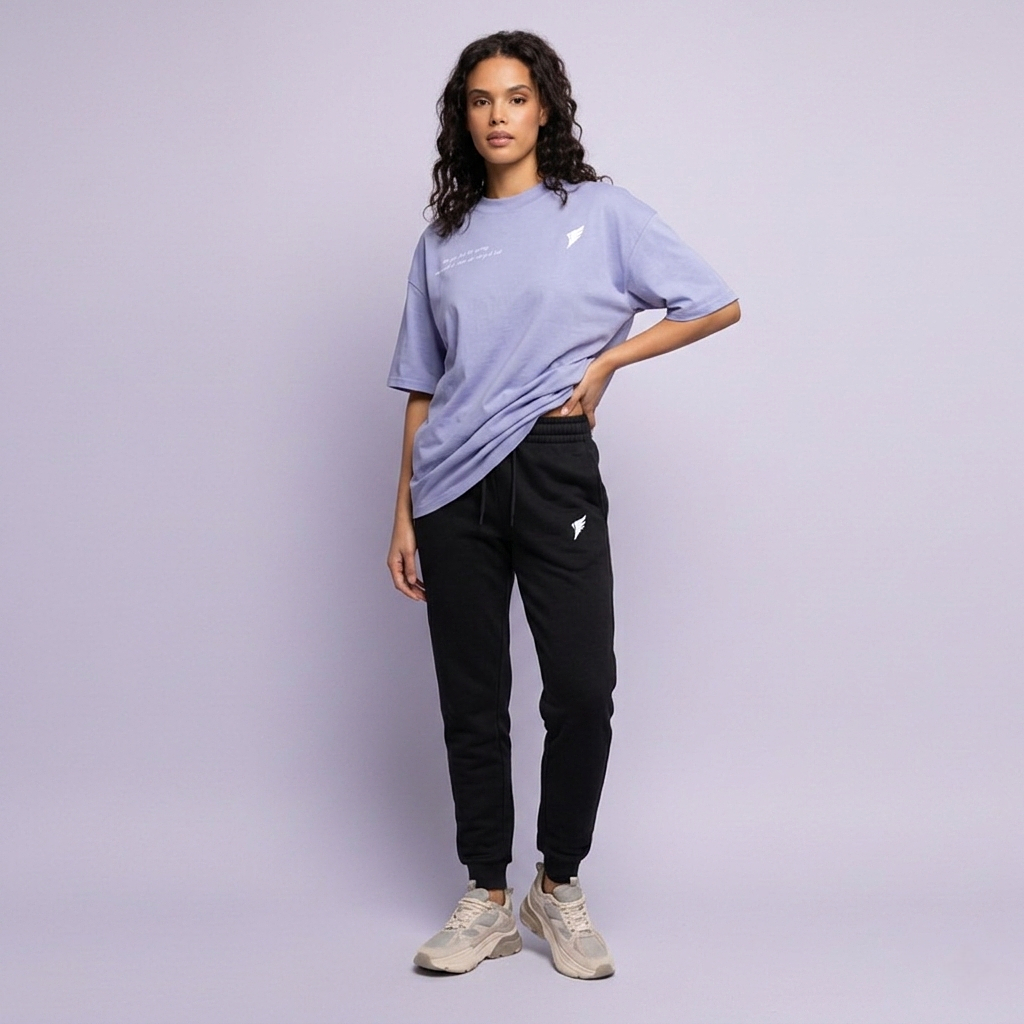 En kvinna i en fotostudio som bär ett par joggers och en lila t-shirt från Sinner Saint
