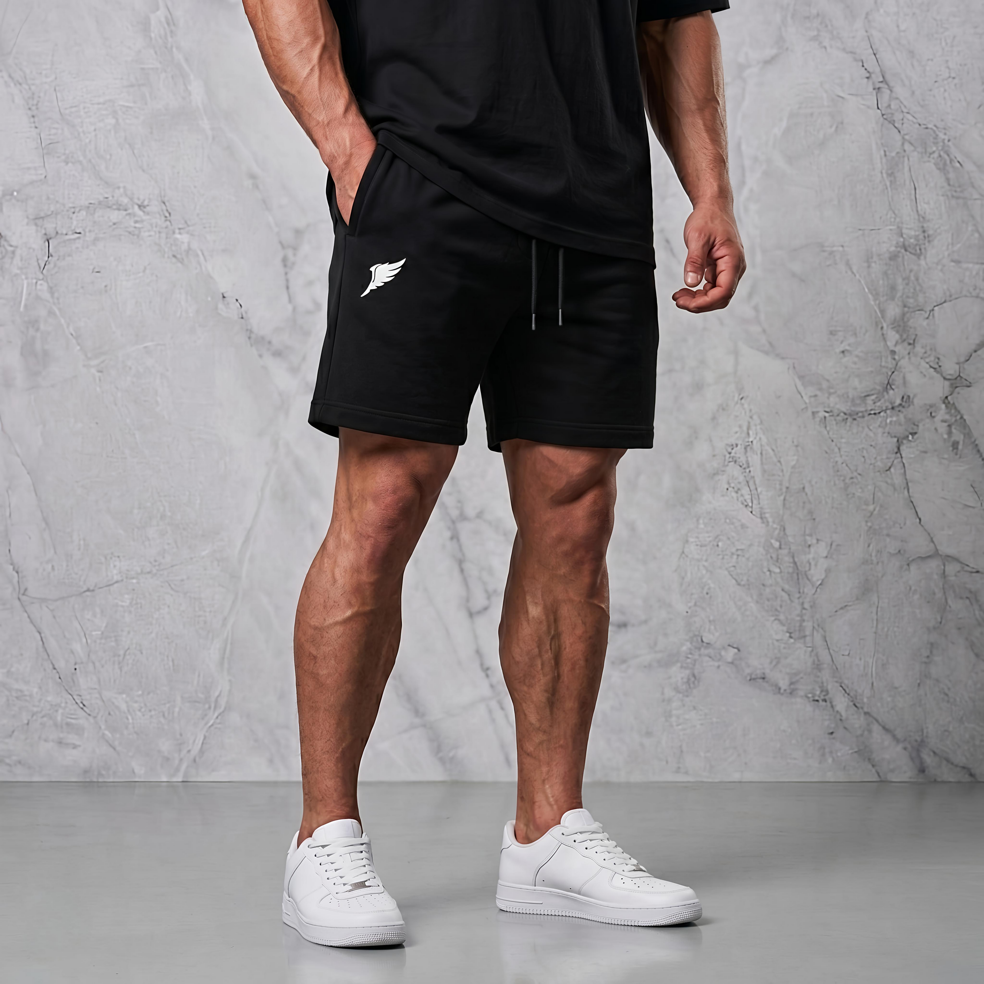 En man i en fotostudio som bär ett par svarta tygshorts gjorda för att gymma i.